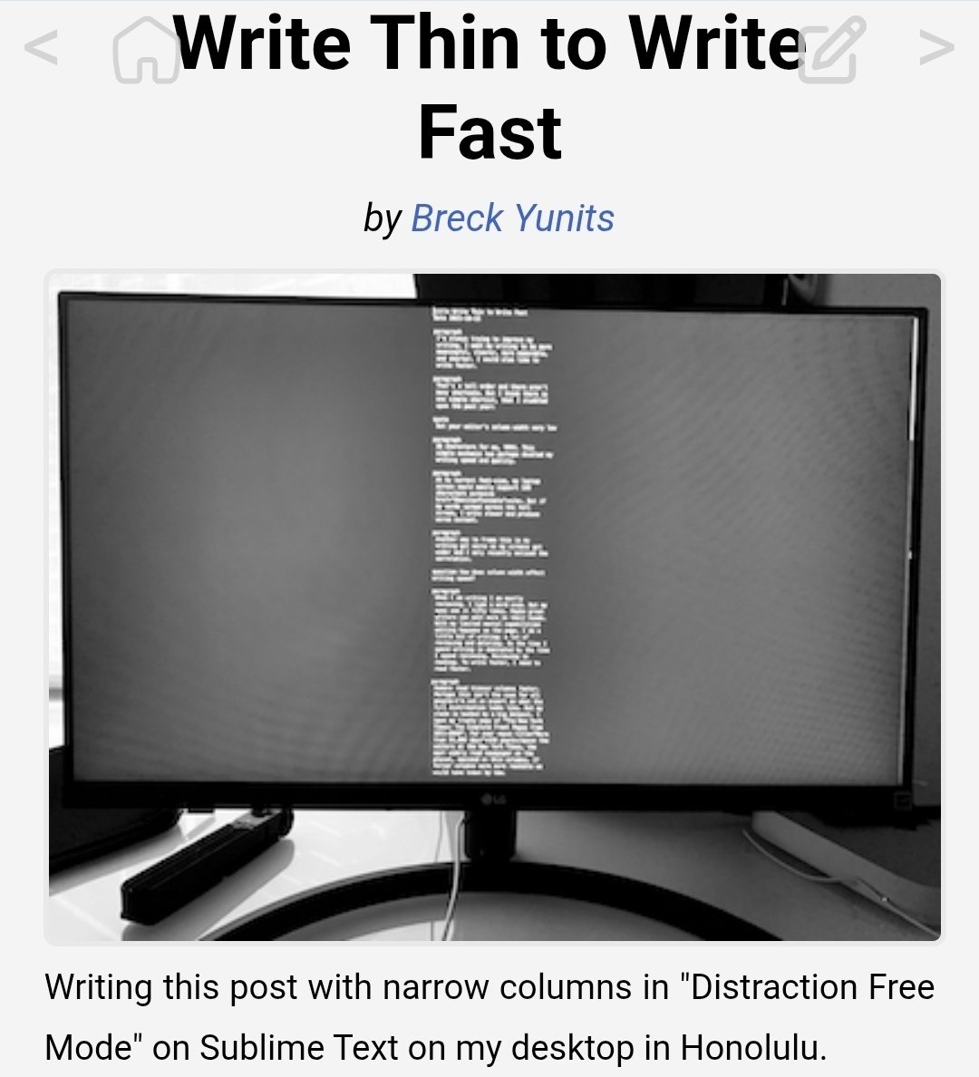 A black-and-white image of a computer monitor displaying a text editor with narrow columns of white text on a dark background, set on a desk with a curved stand.