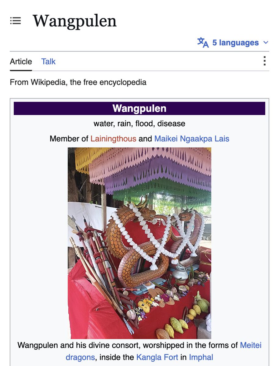 A vibrant image shows a red cloth-covered altar with a large, intricately carved golden dragon and its divine consort, surrounded by ceremonial items including spears, fruits, and a silver pot, under a colorful, layered canopy.