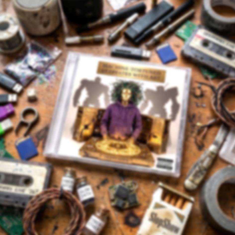 A CD case sits in the center of a cluttered wooden table surrounded by various items like cassette tapes, tools, wires, and small bottles. The CD cover features a person in a purple hoodie with green hair standing behind a golden console, flanked by two large robot silhouettes.